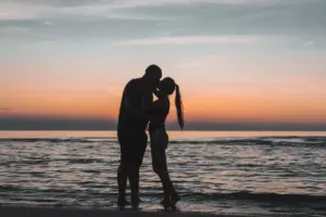 Pareja besándose en la playa al atardecer — la mujer Piscis y su elemento