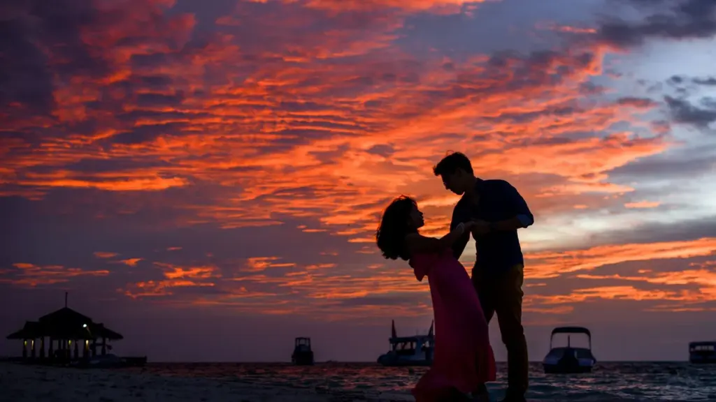 Pareja en silueta en la playa al atardecer en verano