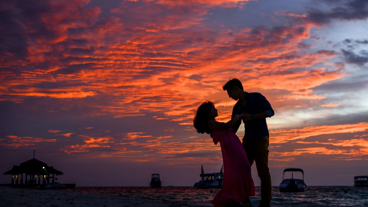 Pareja en silueta en la playa al atardecer en verano